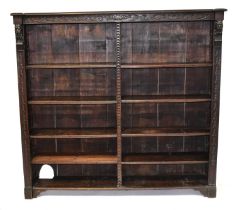 An oak Medieval-style double bookcase, with carved frieze top, sides and centre column and eight