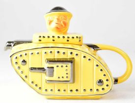 A c.1930s teapot in the form of a tank with driver, yellow with silver lustre highlighting,