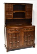 A reproduction oak dresser, the top with central plate rack flanked by two panelled cupboards, on