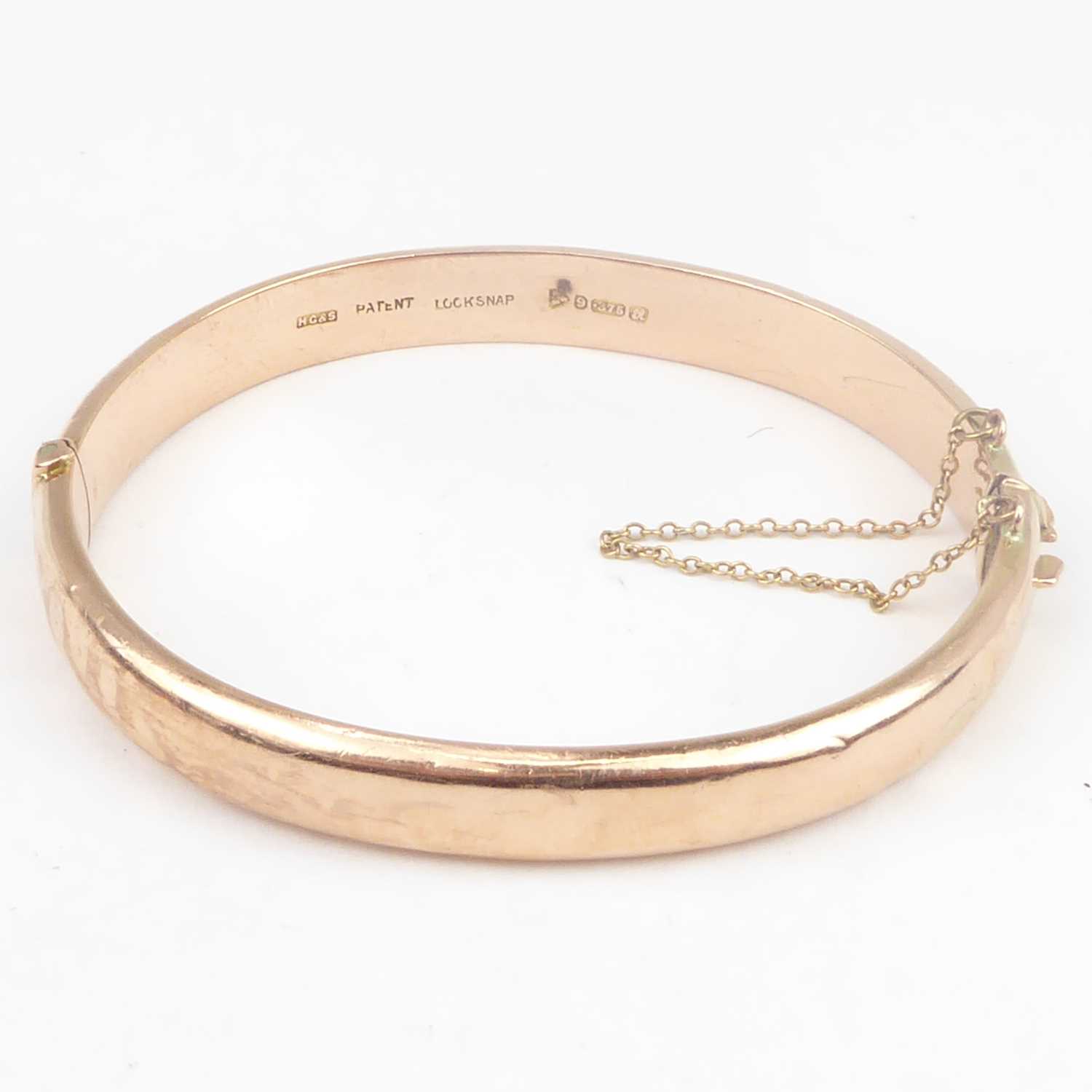 A 9ct rose gold hinged bracelet with safety chain, diameter 6.3cm, approx. 11g. Condition Report: