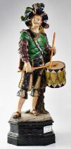 A 19th century Majolica statue of a moustachioed Cavalier carrying a drum, raised on a shaped