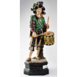 A 19th century Majolica statue of a moustachioed Cavalier carrying a drum, raised on a shaped