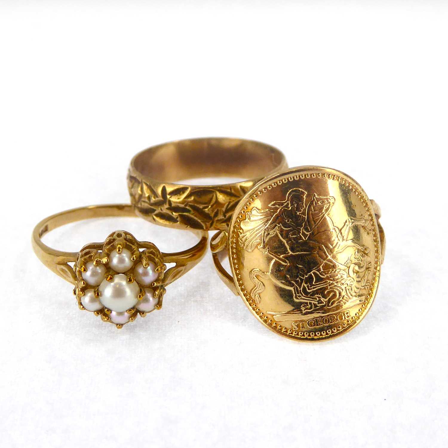 Three 9ct gold rings comprising a seed pearl flower cluster, size M, a 9ct band with textured