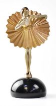 An Art Deco style painted spelter figure of a young lady leaning forward, raised on an ebonised dome