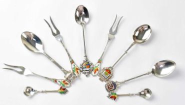 Six silver souvenir spoons and three matching silver cake forks, all but one with enamelled finials,