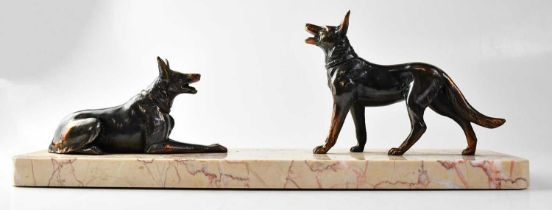 An early 20th century cast metal figure group of two German Shepherds, one standing, the other