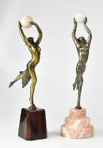 A near pair of early 20th century bronzed figures of female dancers, each holding a ball aloft,