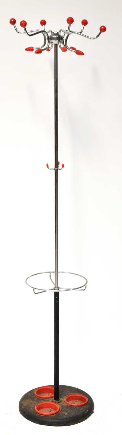 A vintage chrome freestanding coat rack with three red plastic drip trays to the cast iron base, a