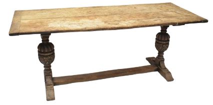 A 19th century oak plank top refectory table on carved cup and cover legs united by a stretcher,