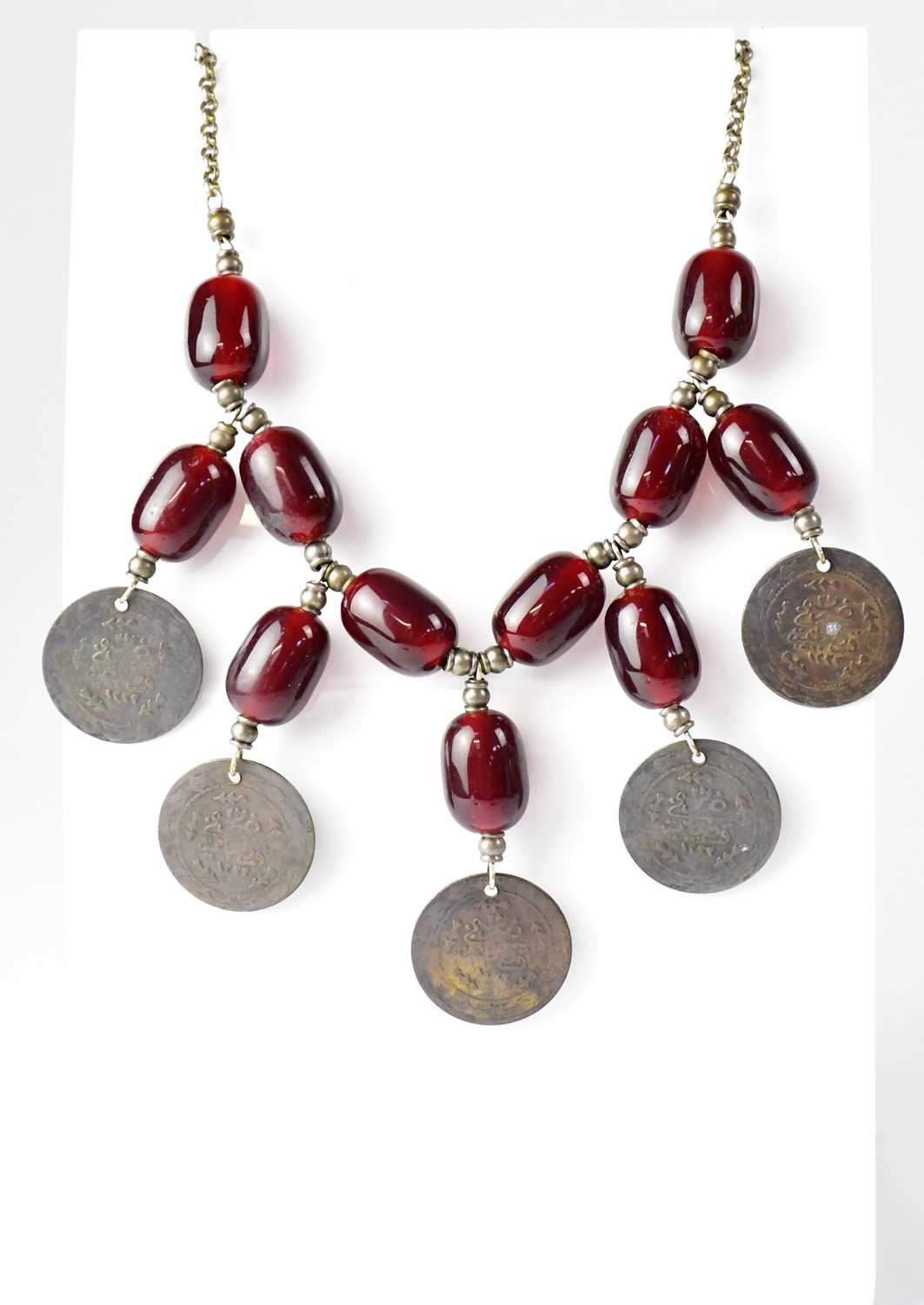 A Turkish cherry amber coloured bead necklace set with five Turkish coins on a white metal chain,