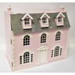 A pink painted three-storey double-fronted dolls' house, with three dormer windows, 70 x 73 x 40cm.