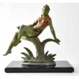 A painted cast metal figure of a young lady sitting on a tree stump, unsigned, on associated black