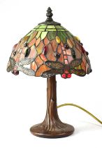 A small Tiffany-style table lamp with leaded stained glass shade, with dragonflies, raised on a