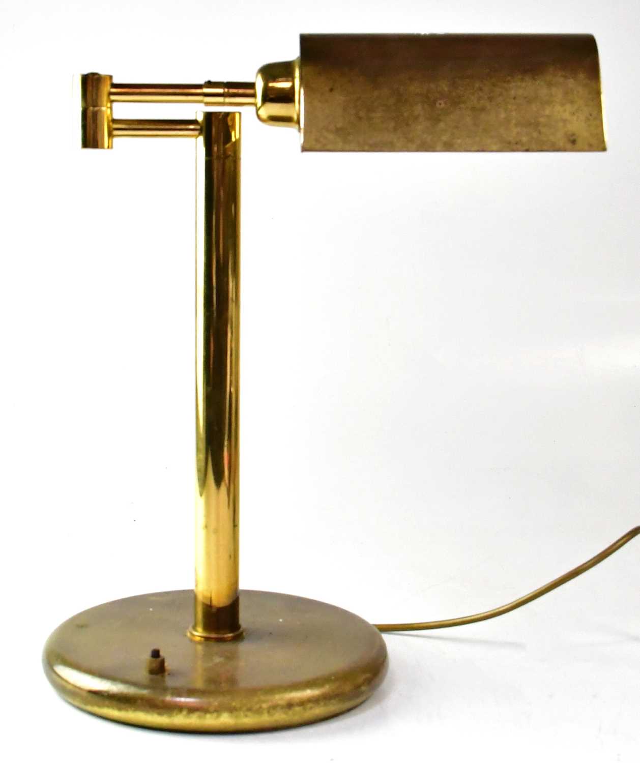 A brass reading lamp with adjustable brass shade, on two swinging arms to circular base, height