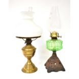 Two vintage oil lamps, comprising a cast metal example with green glass reservoir and a brass