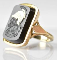 A 9ct gold ring with engraved black stone panel depicting a Greek warrior with yellow metal inlaid