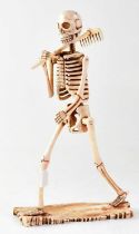 A large carved bone model of a skeleton carrying a rake, height 29cm.