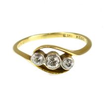 An 18ct gold three-stone diamond ring, the three small bezel set brilliant cut diamonds in a