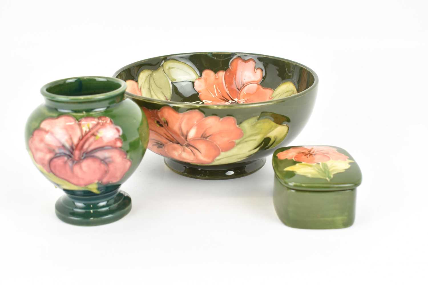 WALTER MOORCROFT; three pieces of 'Hibiscus' pattern tube-lined pottery on green ground,