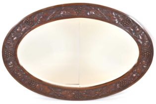 An oval oak bevel edged mirror, the frame carved with grapes and vines, 92 x 62cm.