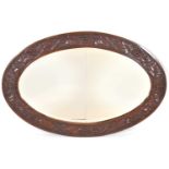 An oval oak bevel edged mirror, the frame carved with grapes and vines, 92 x 62cm.