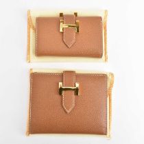 HERMÈS, PARIS; two boxed brown leather key-holders with zipped pockets, with bag and box (2).