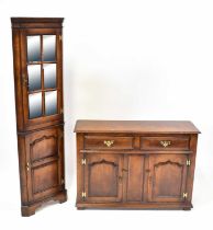 A reproduction oak small sideboard with two drawers over two cabinets with brass hinges and swing