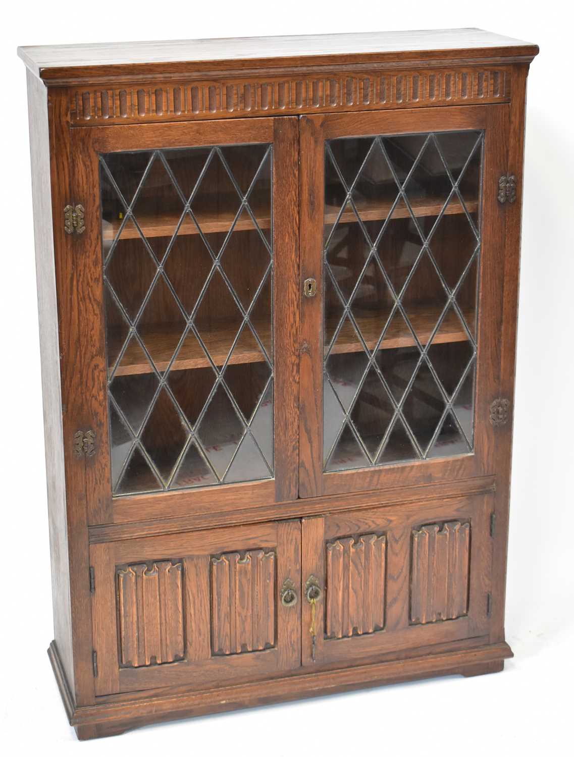 A mid-20th century oak cabinet with leaded glazed doors, above a pair of carved linenfold doors, 137