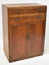 A 1940s oak side cabinet with two drawers above a pair of panelled doors, raised on a plinth base,