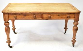 A rustic pine farmhouse table with two frieze drawers to one side, raised on turned supports to