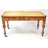 A rustic pine farmhouse table with two frieze drawers to one side, raised on turned supports to