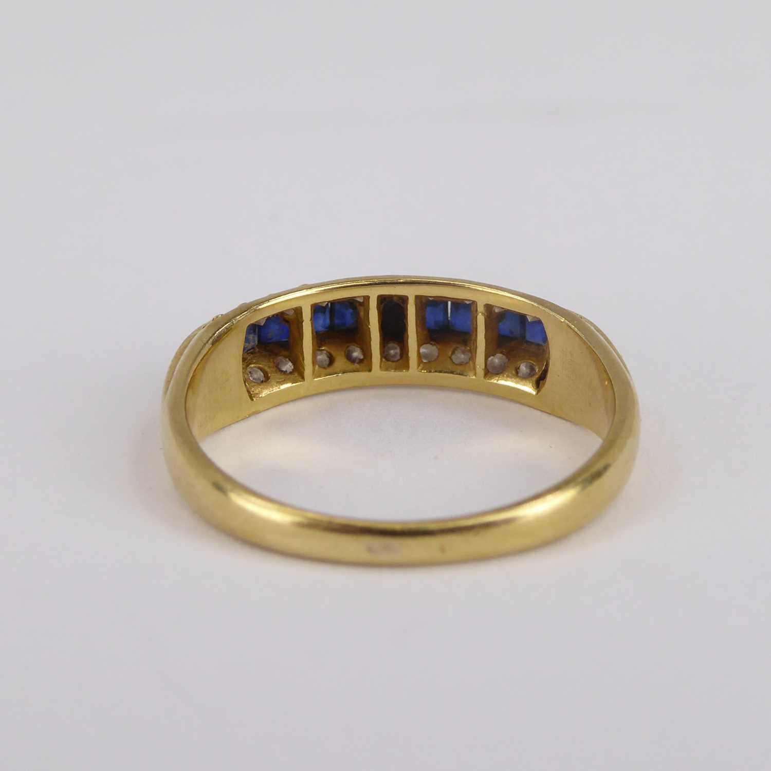 An 18ct gold diamond and sapphire ring, the four central channel set square cut sapphires flanked by - Image 9 of 9