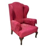 An early 20th century Georgian-style mahogany framed wing armchair, upholstered in a red damask