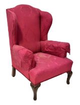 An early 20th century Georgian-style mahogany framed wing armchair, upholstered in a red damask