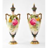 ROYAL WORCESTER; a pair of twin-handled lidded vases on circular footed base, painted with roses