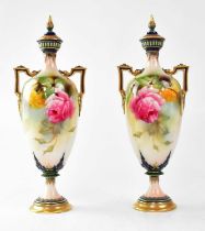 ROYAL WORCESTER; a pair of twin-handled lidded vases on circular footed base, painted with roses