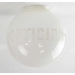 An opaque white glass globe shade etched with the word 'Optician', height 25cm.