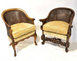 Two double cane walnut armchairs with curved backs terminating in acanthus leaf scroll arms,