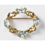 An oval yellow metal brooch set with aquamarine and seed pearls in an openwork foliate setting,