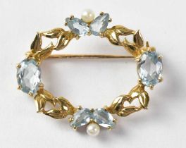 An oval yellow metal brooch set with aquamarine and seed pearls in an openwork foliate setting,