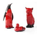 ROYAL DOULTON; three red flambé glazed figures comprising a seated cat, height 13cm, penguin, height