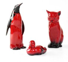 ROYAL DOULTON; three red flambé glazed figures comprising a seated cat, height 13cm, penguin, height