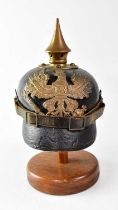 A WWI Prussian M1915 pickelhaube on stand (af). Condition Report: Leather cracking throughout, brass