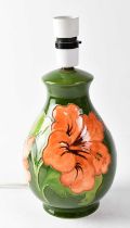 MOORCROFT; a 'Hibiscus' pattern lamp base on green ground, height including fitment 27.5cm, with