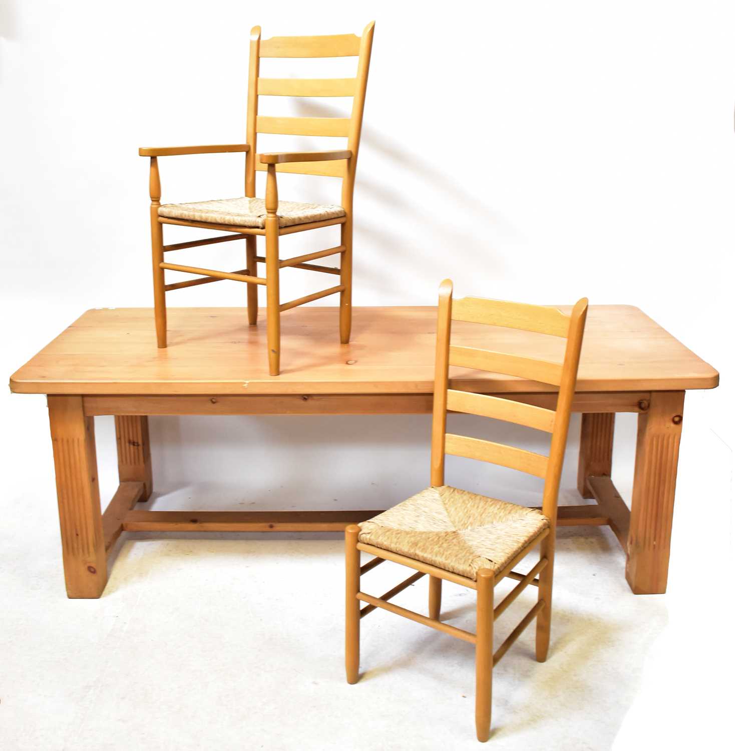 A large pine kitchen/dining table with square carved reeded legs, united by a stretcher, 76 x 214