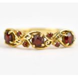 A 9ct gold ring set with three claw set garnets separated by two rows of two diagonal smaller