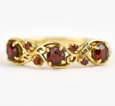 A 9ct gold ring set with three claw set garnets separated by two rows of two diagonal smaller
