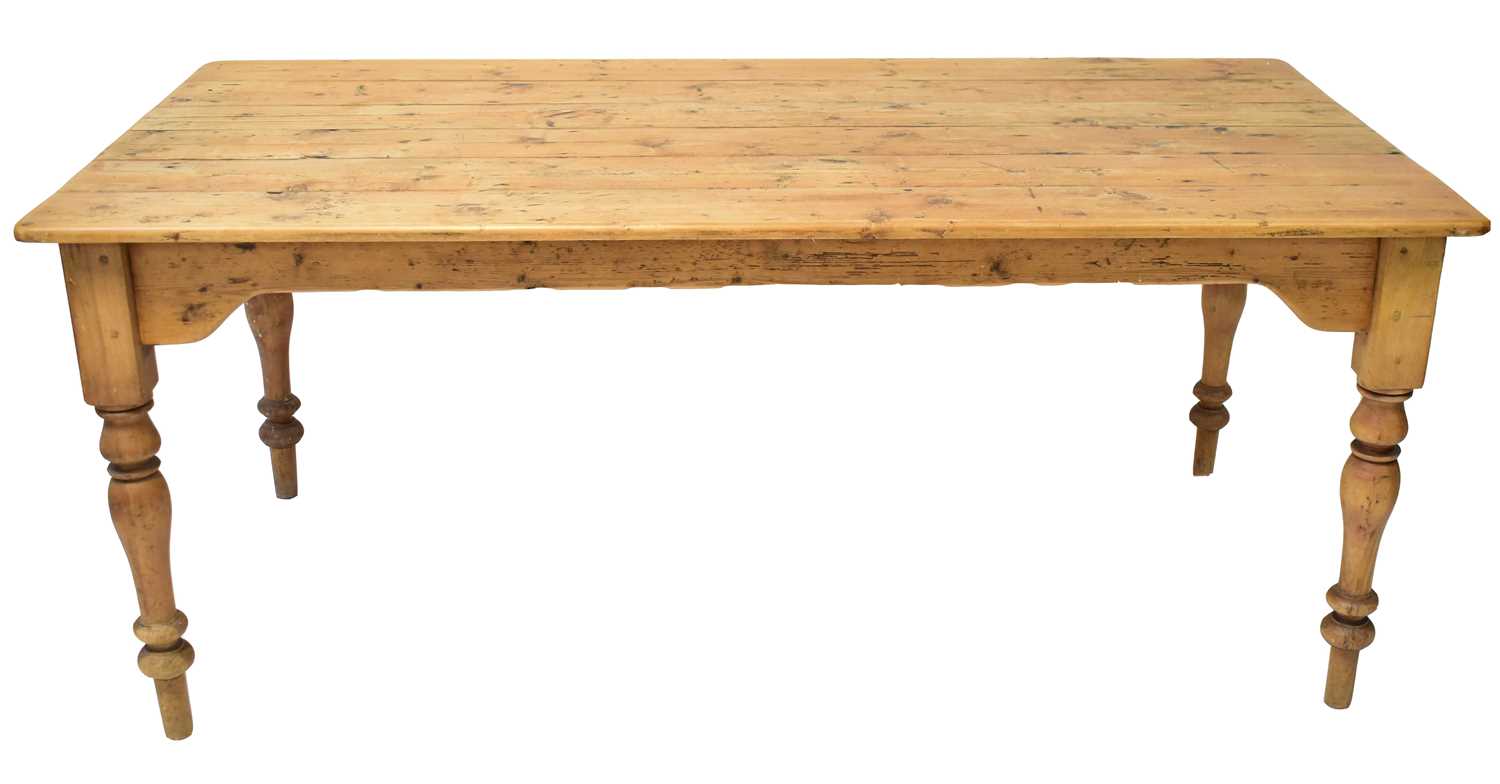 A large rustic pine farmhouse table of plank top construction, raised on turned tapering supports,