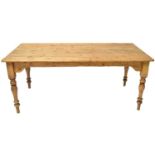 A large rustic pine farmhouse table of plank top construction, raised on turned tapering supports,