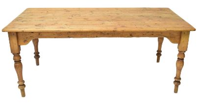 A large rustic pine farmhouse table of plank top construction, raised on turned tapering supports,